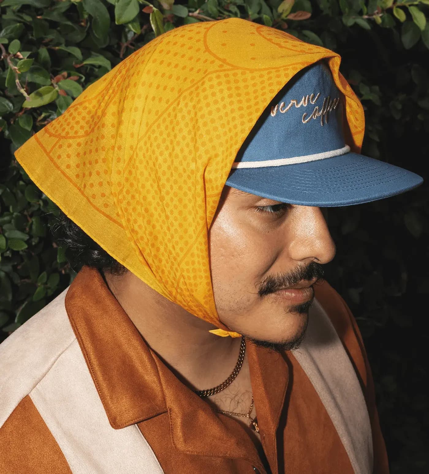 Verve Culture yellow custom bandana styled over a cap in an outdoor portrait