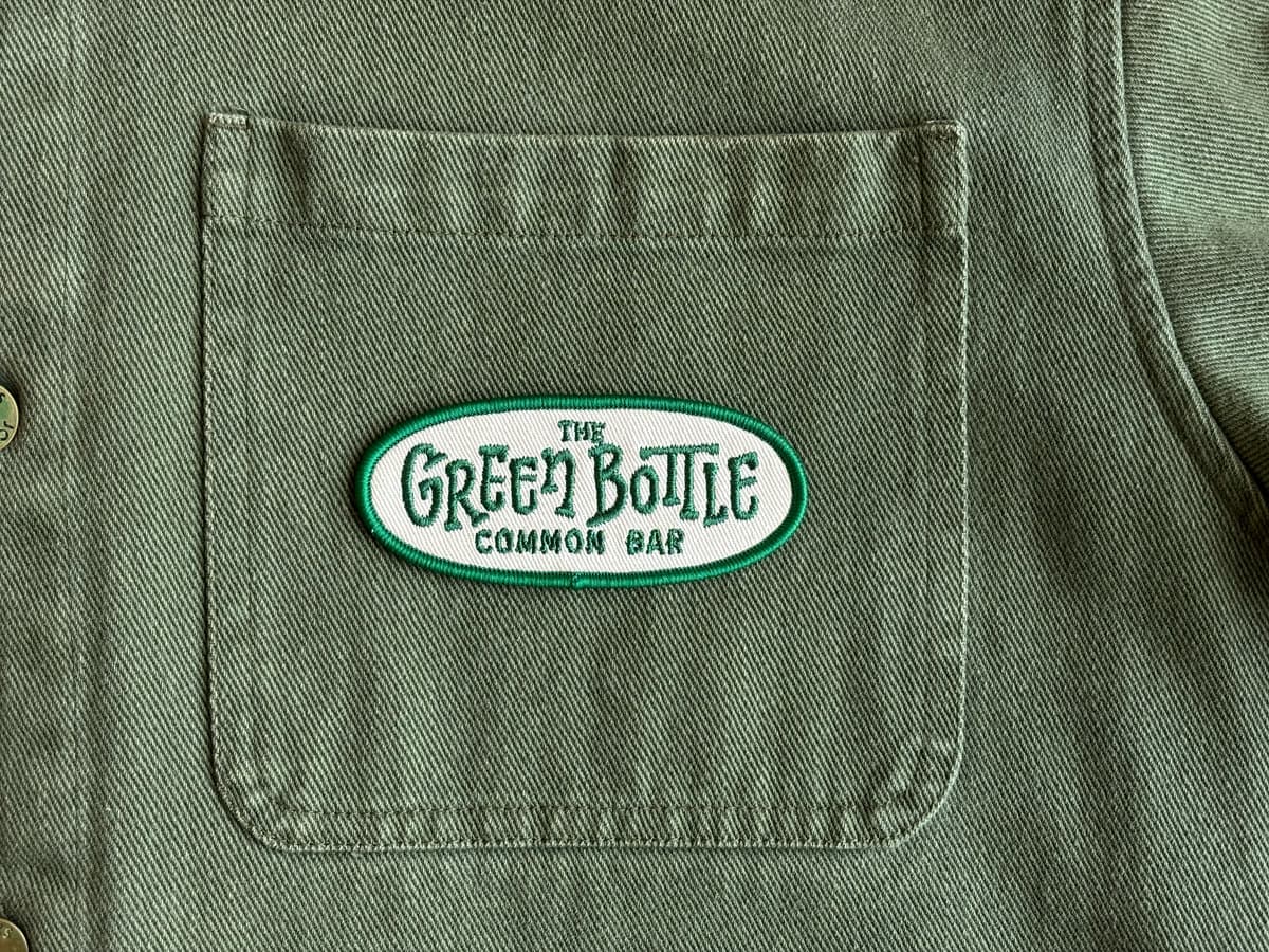 Green Bottle patch sewn onto an apparel pocket as a mixed-decoration example