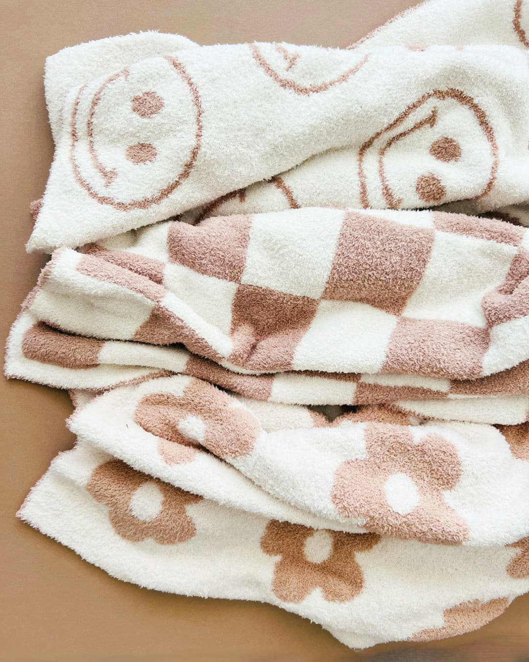 Soft daisy-pattern fleece blanket folded on a warm neutral backdrop