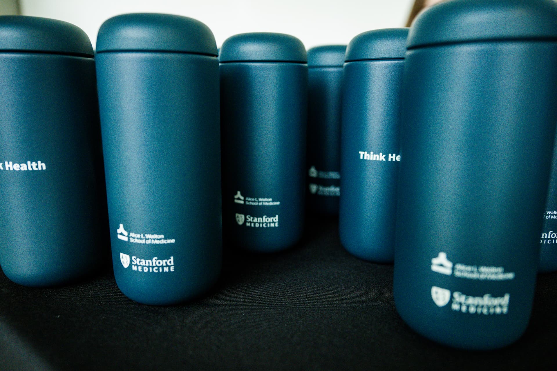 Matte blue Stanford Medicine tumblers lined up on a table
