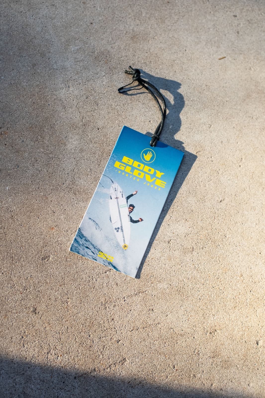Body Glove hang tag with black string laid on a concrete surface
