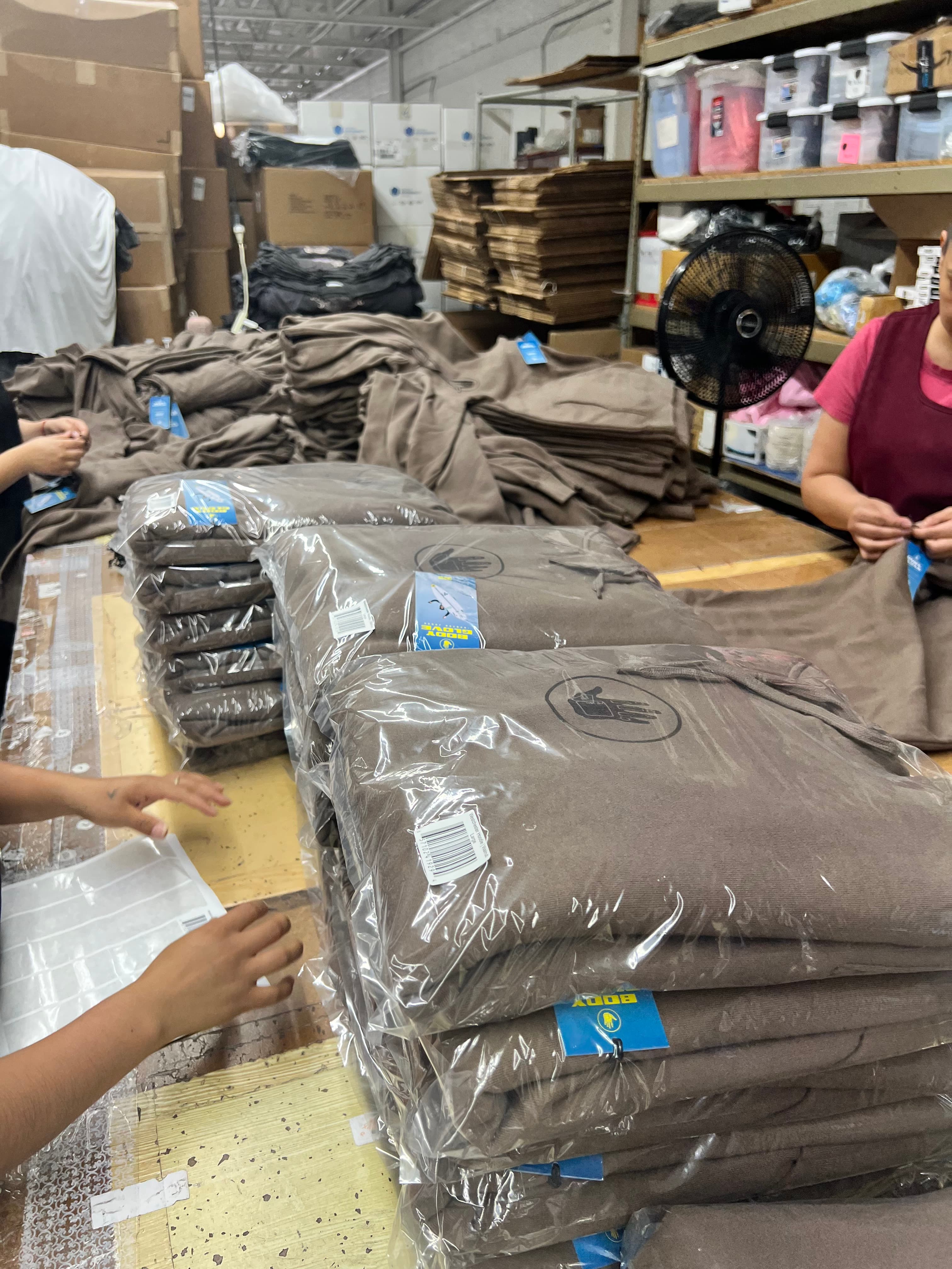 Stacks of folded screen printed garments individually packed in clear poly bags