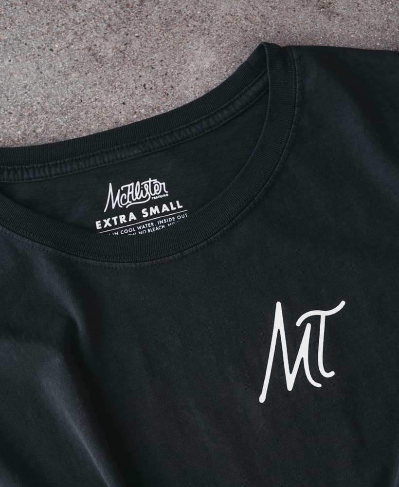 Printed neck label inside a black tee, cropped to keep the interior branding detail clear while showing a bit of the garment front